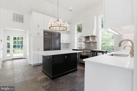 a kitchen with stainless steel appliances a sink a stove and a chandelier