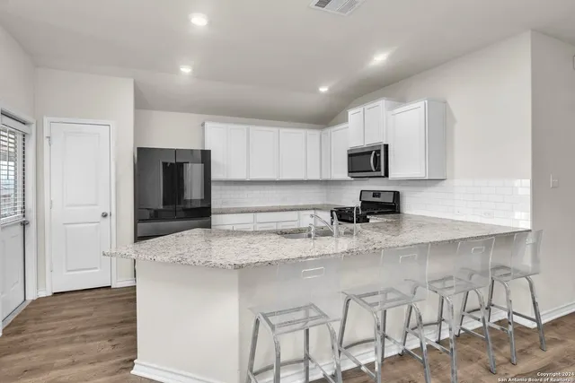 a kitchen with granite countertop white cabinets and stainless steel appliances