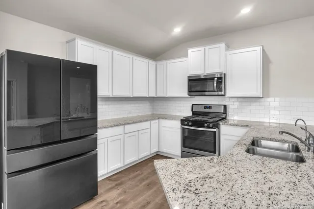 a kitchen with stainless steel appliances granite countertop a refrigerator stove a sink and a microwave