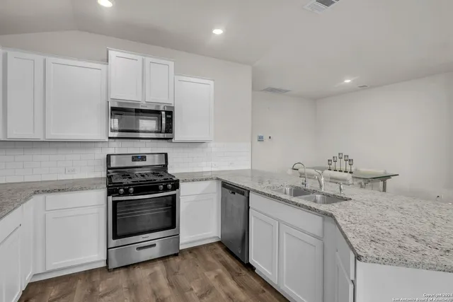a kitchen with stainless steel appliances granite countertop a sink stove oven and white cabinets