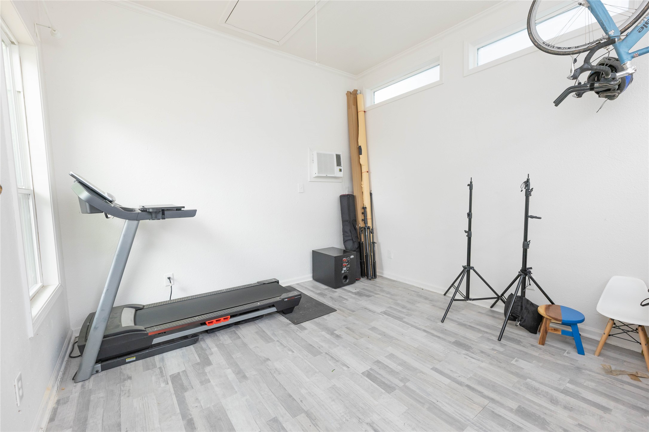 8007 Capitol Street Houston, TX 77012 - Photo 25 of 25 Bright multipurpose room featuring light wood flooring, a treadmill, and storage space. Ideal for workouts or hobbies, with natural light from large windows and additional upper windows.