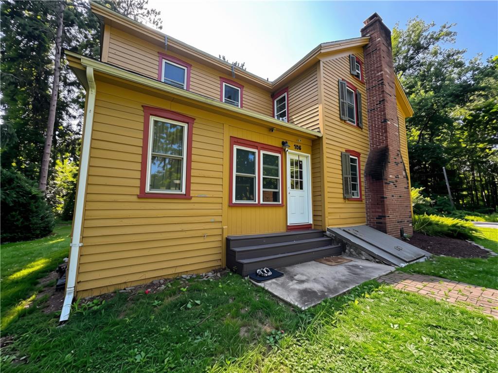 A charming yellow home with striking red trim and a prominent brick chimney awaits.