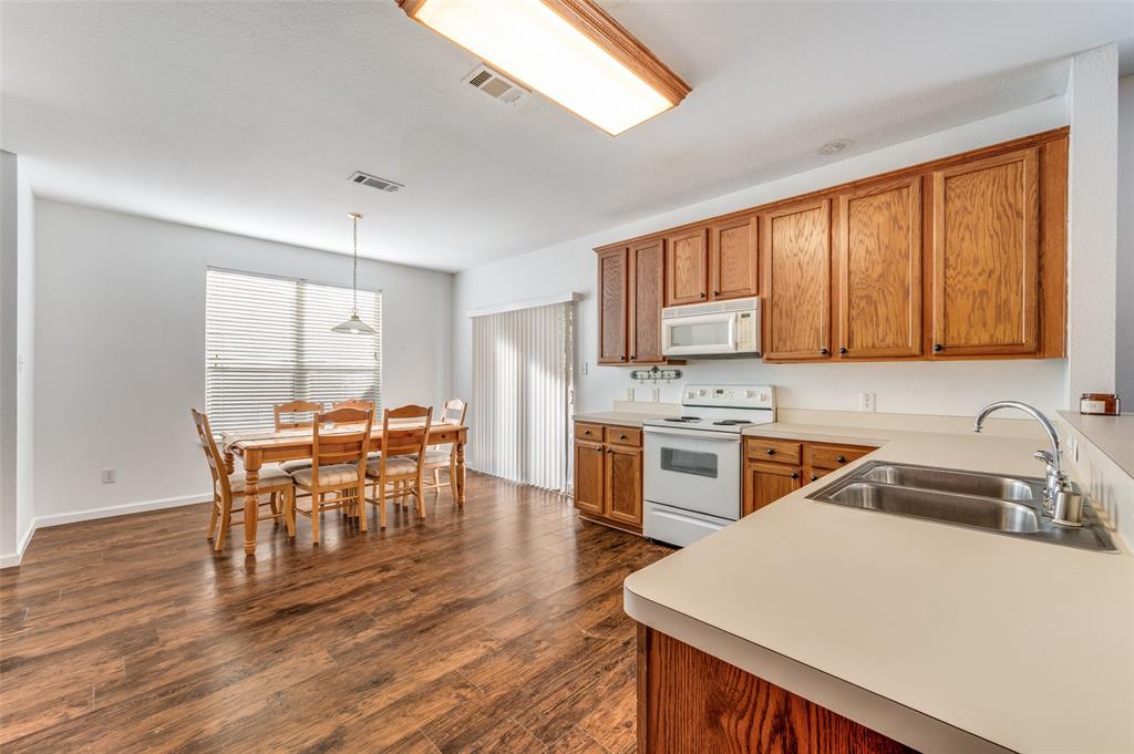 2516 Quail Ridge Road Melissa, TX 75454 - Photo 19 of 30 a kitchen with a table chairs a sink dishwasher stove and cabinets with wooden floor