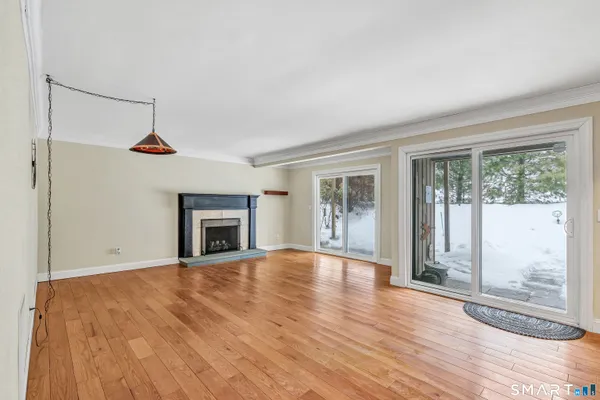 an empty room with wooden floor fireplace and windows