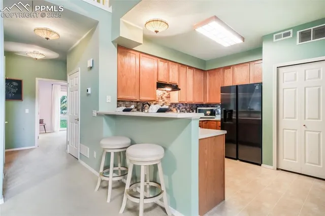 a kitchen with stainless steel appliances granite countertop a stove a refrigerator a sink a dining table and chairs with wooden floor