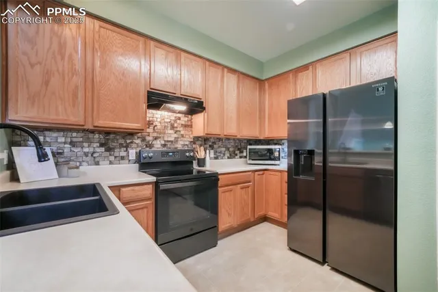 a kitchen with stainless steel appliances granite countertop a refrigerator a stove and a sink