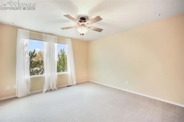 an empty room with windows and chandelier fan