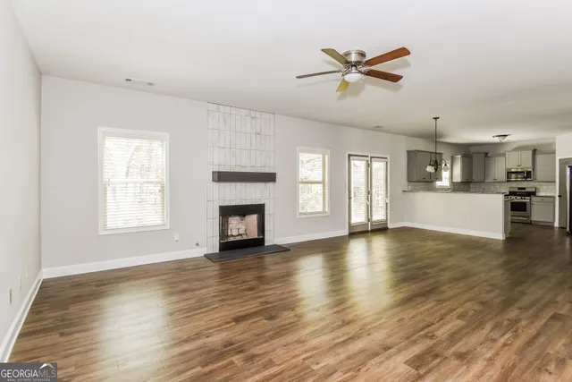 a view of an empty room with a kitchen and wooden floor