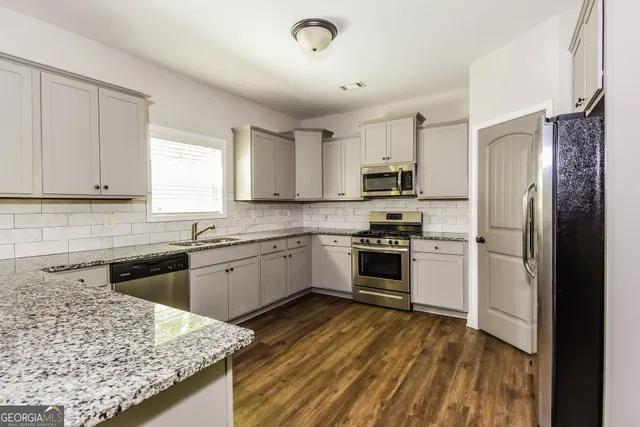 a kitchen with granite countertop a refrigerator stove top oven and sink