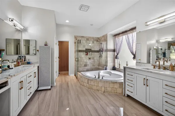 a bathroom with a double vanity sink a mirror a bathtub and shower