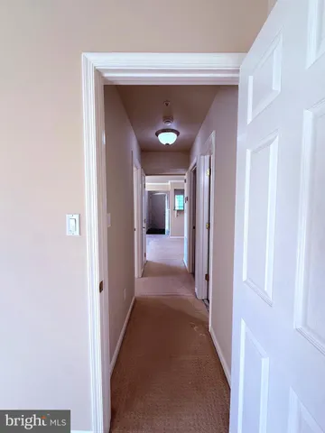 a view of a hallway with wooden floor and a bathroom