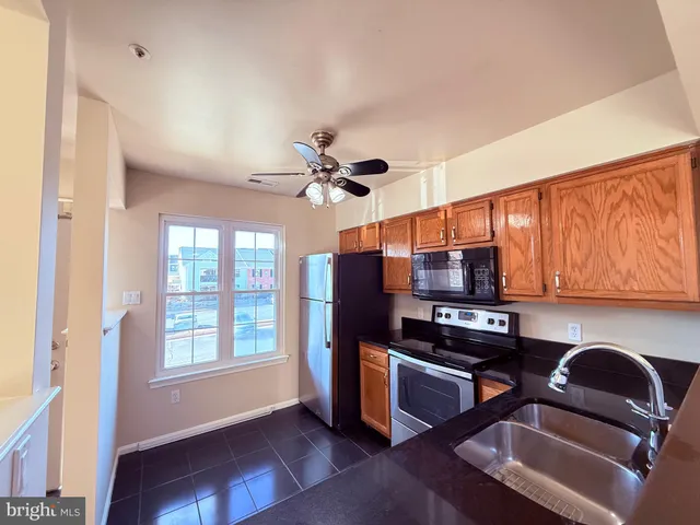 a kitchen with stainless steel appliances granite countertop a refrigerator a sink dishwasher a stove and a dining table with wooden floor