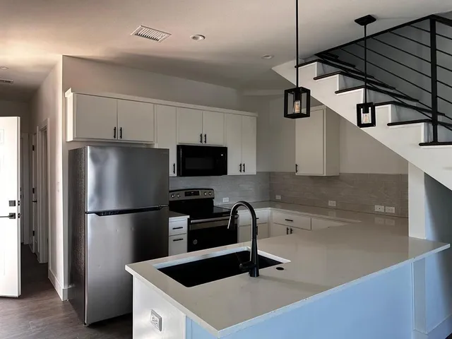 a kitchen with stainless steel appliances a refrigerator a sink and white cabinets