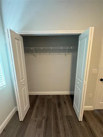a view of an empty room with closet and wooden floor