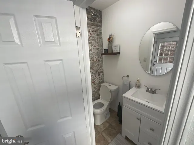 a bathroom with a granite countertop sink a toilet and a mirror