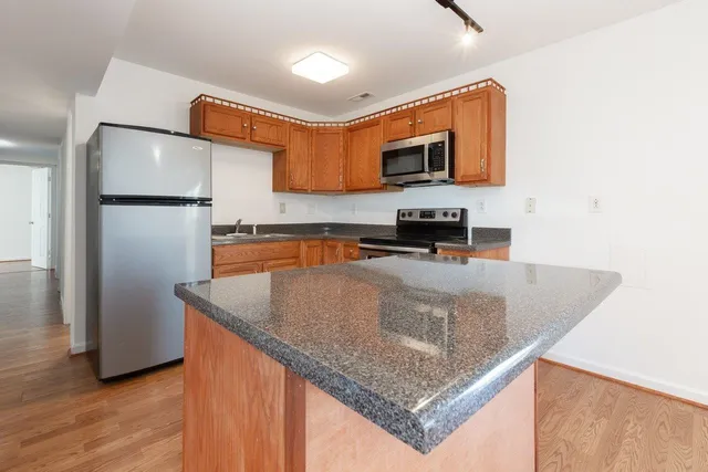 a kitchen with stainless steel appliances granite countertop a refrigerator a sink and a stove