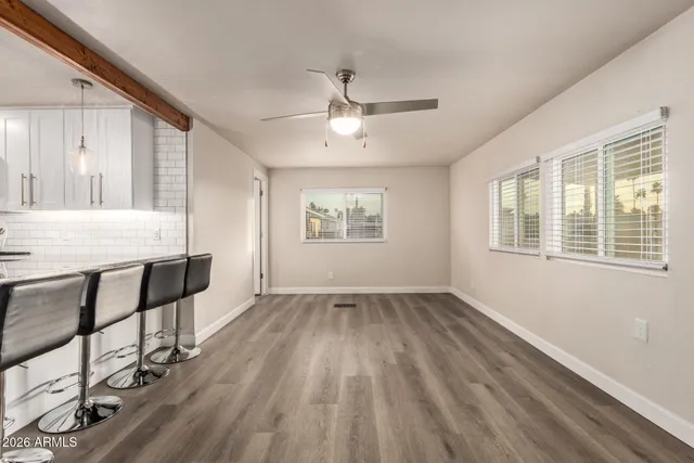 a view of an empty room with window and wooden floor