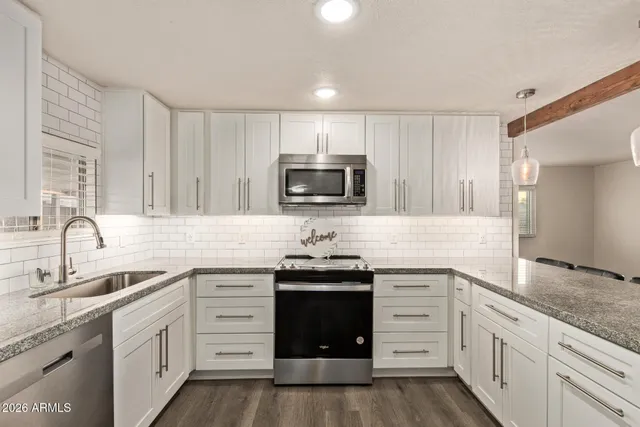 a kitchen with granite countertop white cabinets and stainless steel appliances
