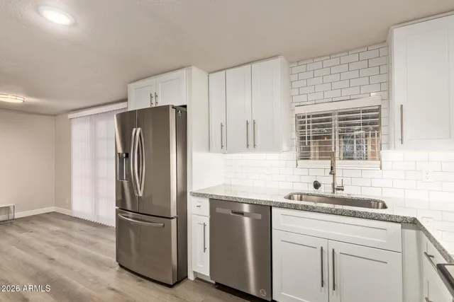 a kitchen with granite countertop a refrigerator sink and cabinets