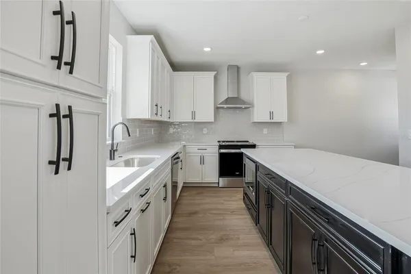 a large kitchen with stainless steel appliances granite countertop a lot of counter space and wooden floors