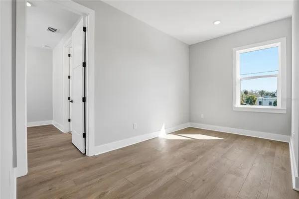 an empty room with wooden floor and windows