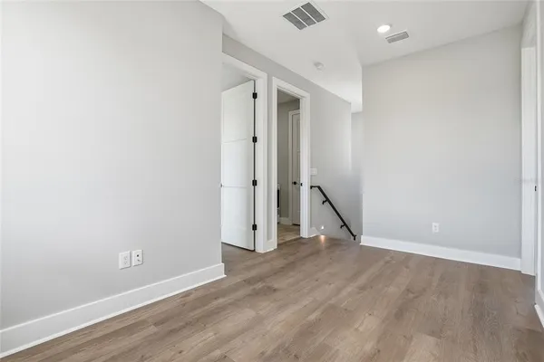 an empty room with wooden floor and a ceiling fan