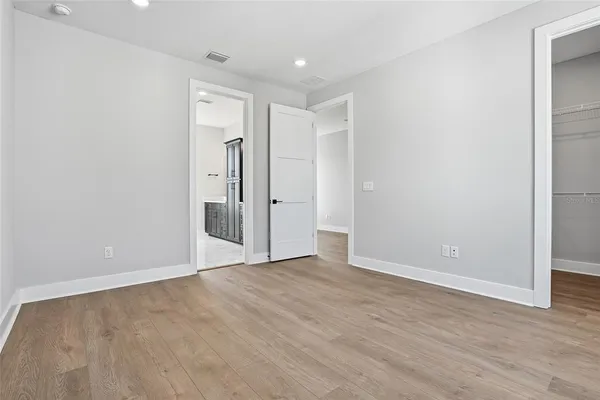 a view of an empty room with wooden floor and closet
