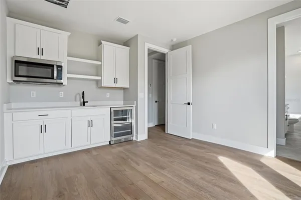 a kitchen with stainless steel appliances white cabinets and wooden floors