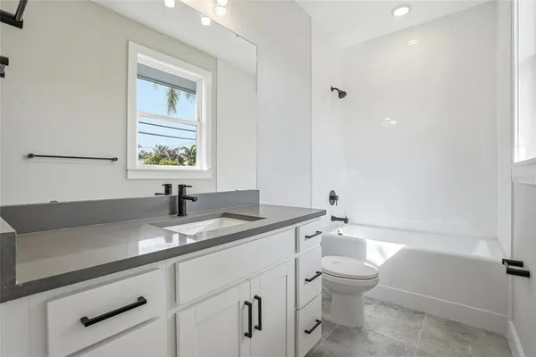 a bathroom with a granite countertop toilet a sink and a bathtub