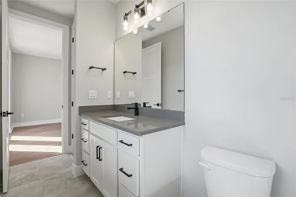 a bathroom with a granite countertop sink a toilet and a mirror