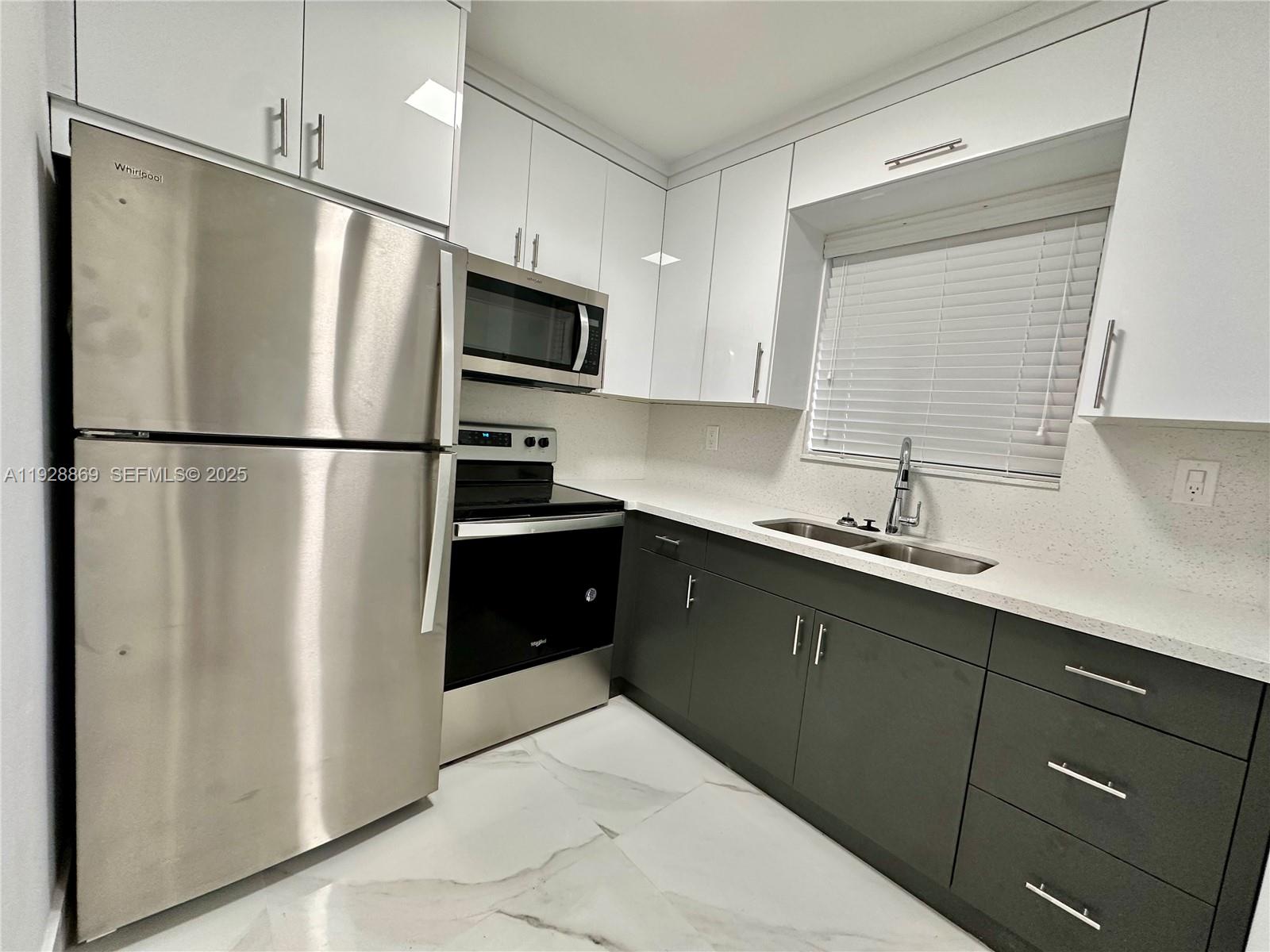 1629 Southwest 3rd Street, Unit 5 Miami, FL 33135 - Photo 18 of 24 a kitchen with a refrigerator sink and white cabinets