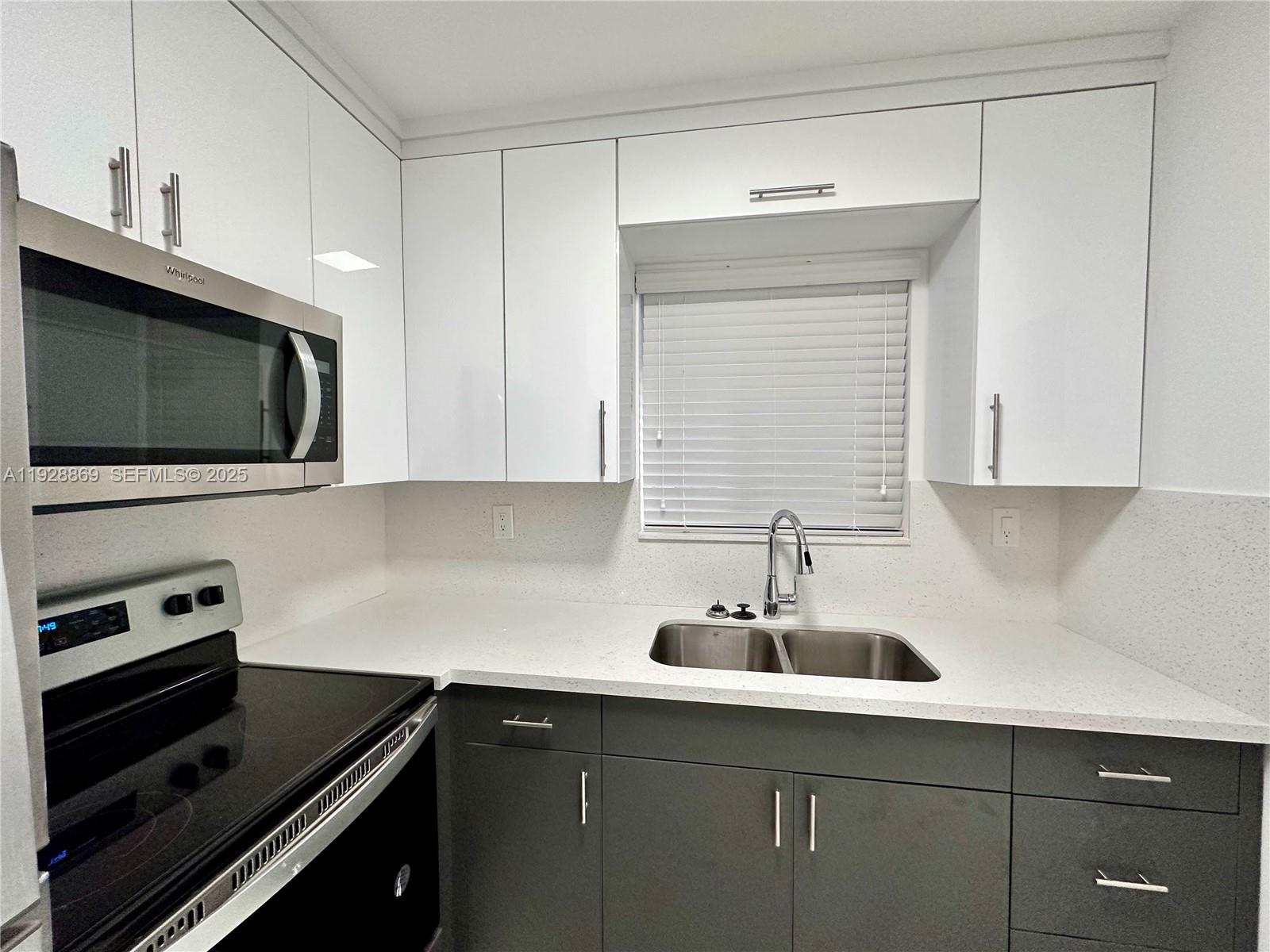 1629 Southwest 3rd Street, Unit 5 Miami, FL 33135 - Photo 19 of 24 a kitchen with stainless steel appliances a sink a stove a microwave and cabinets