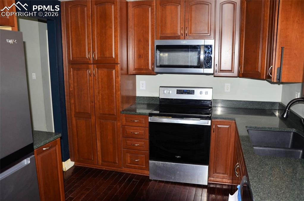 4506 Ranch Circle Colorado Springs, CO 80918 - Photo 3 of 15 a kitchen with granite countertop wooden cabinets stainless steel appliances and a sink