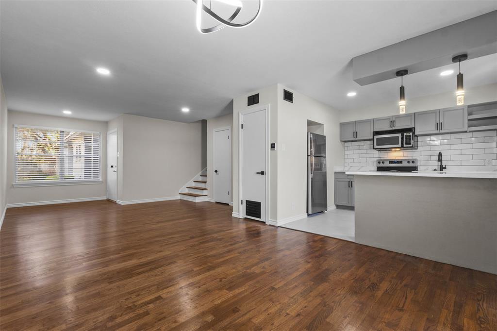 4941 North Hall Street Dallas, TX 75235 - Photo 18 of 18 Kitchen featuring gray cabinetry, open floor plan, light countertops, hanging light fixtures, and dark wood-style flooring