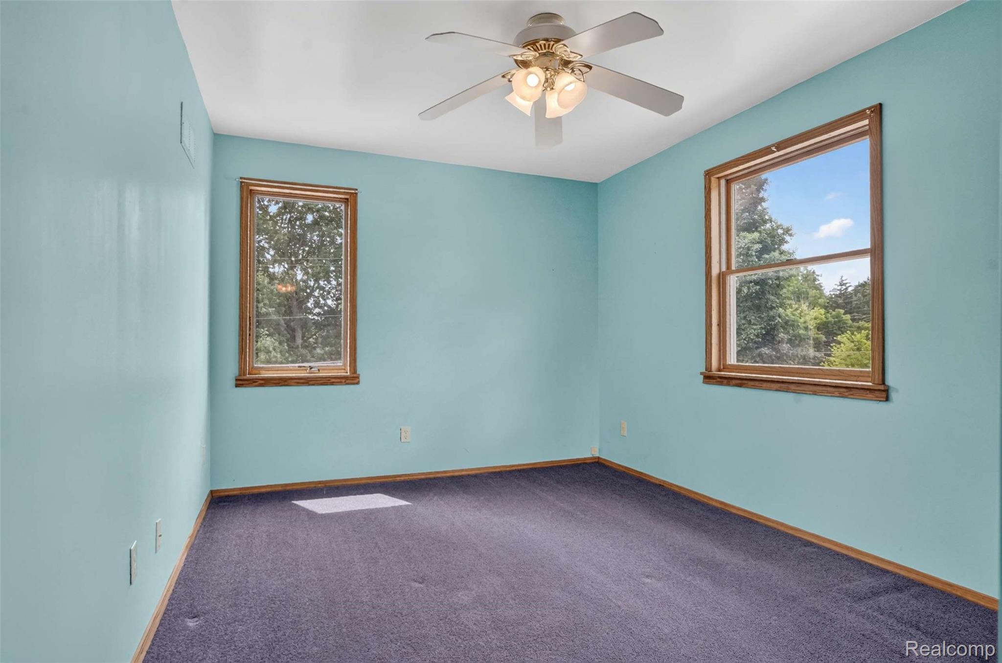 1437 East Cook Road Grand Blanc, MI 48439 - Photo 62 of 69 Room featuring two double-hung windows with natural wood trim, wall-to-wall carpeting, and a ceiling fan with integrated lighting
