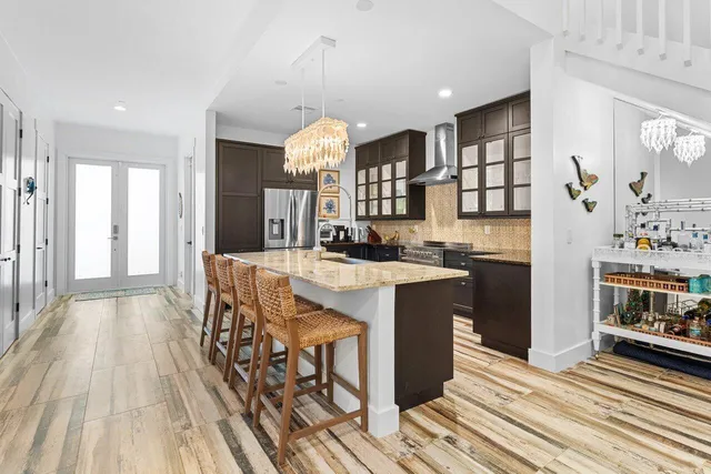 a kitchen with stainless steel appliances granite countertop a refrigerator a sink dishwasher a stove and a dining table with wooden floor