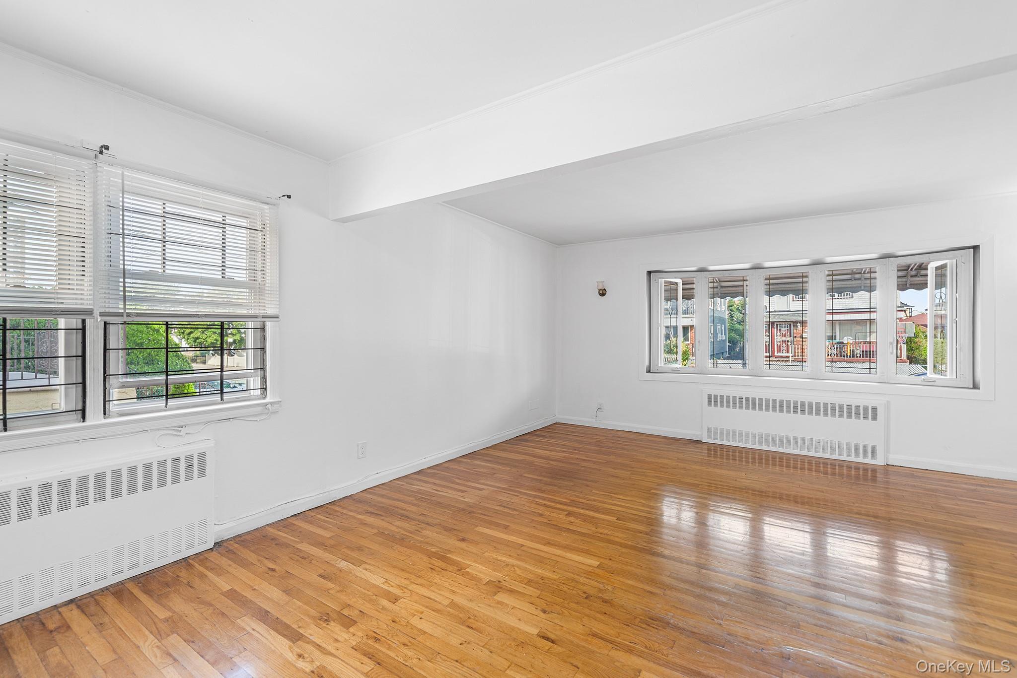 27-11 Deerfield Road Queens, NY 11691 - Photo 11 of 43 a view of an empty room with wooden floor and a window