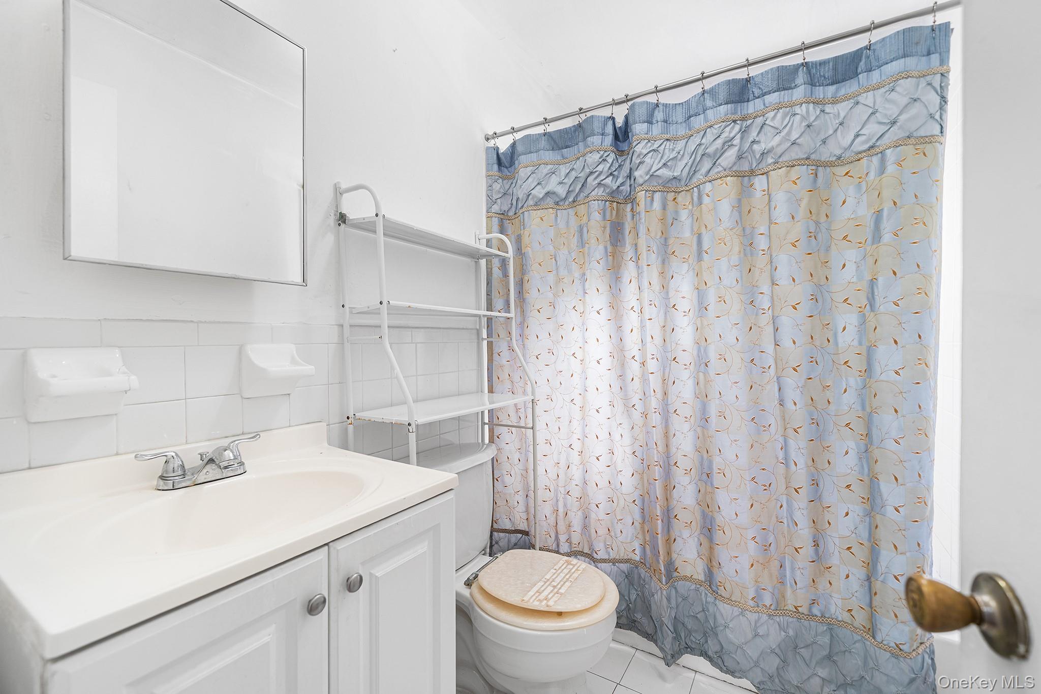 27-11 Deerfield Road Queens, NY 11691 - Photo 17 of 43 a bathroom with a sink a toilet and shower curtain
