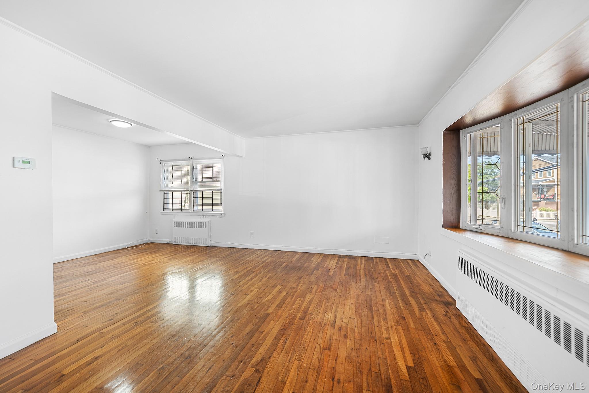 27-11 Deerfield Road Queens, NY 11691 - Photo 5 of 43 an empty room with wooden floor and windows