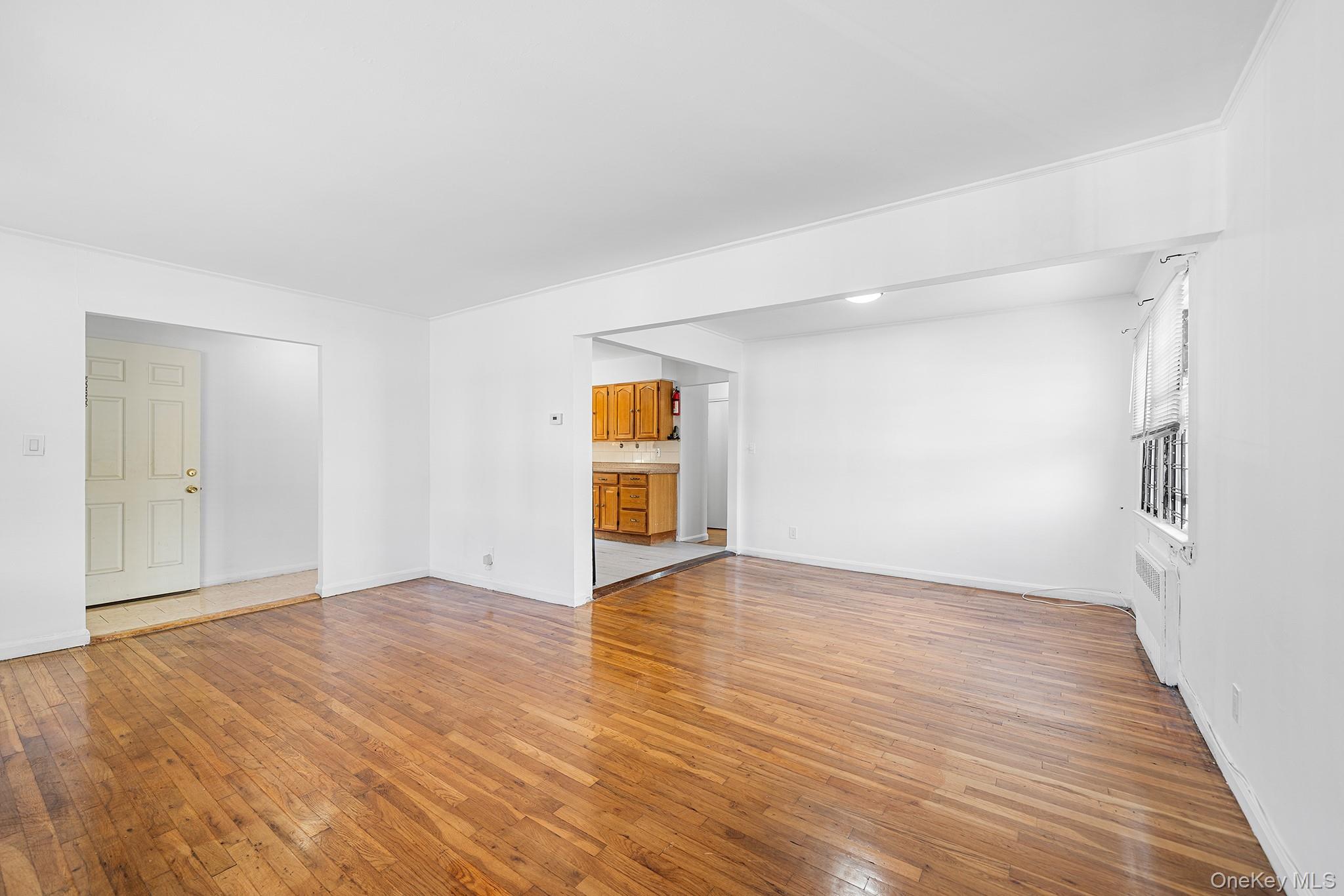 27-11 Deerfield Road Queens, NY 11691 - Photo 6 of 43 a view of an empty room with wooden floor and a window