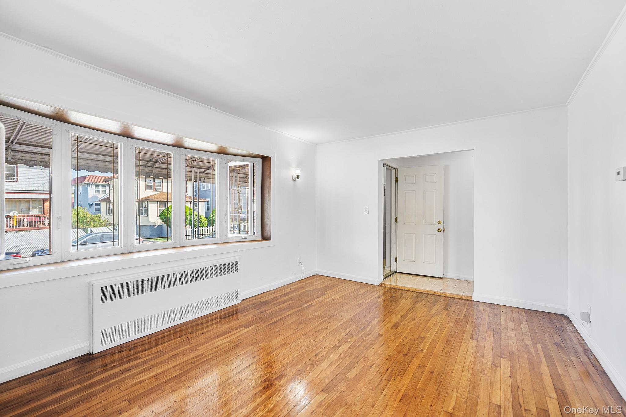 27-11 Deerfield Road Queens, NY 11691 - Photo 7 of 43 a view of an empty room with wooden floor and a window