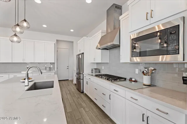 a kitchen with stainless steel appliances a sink a stove a microwave cabinets and a counter top space