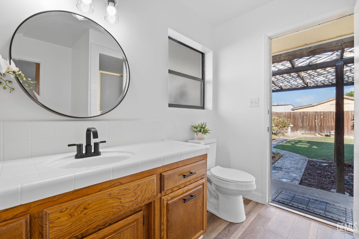 Undisclosed Address Bakersfield, CA 93314 - Photo 42 of 60 a bathroom with a sink a mirror a toilet and a window