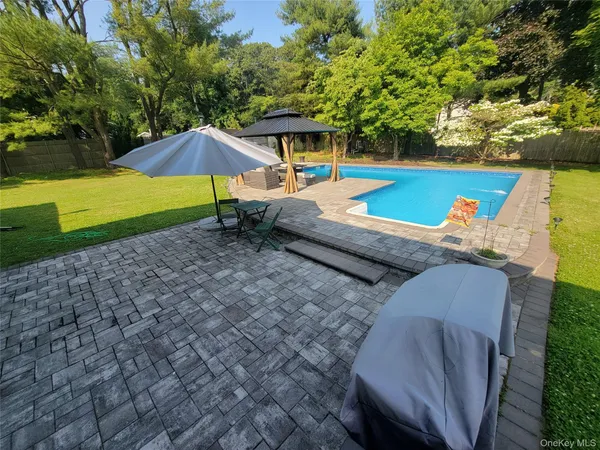 a backyard of a house with table and chairs under an umbrella