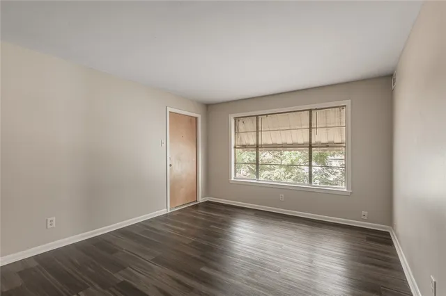 an empty room with wooden floor and window