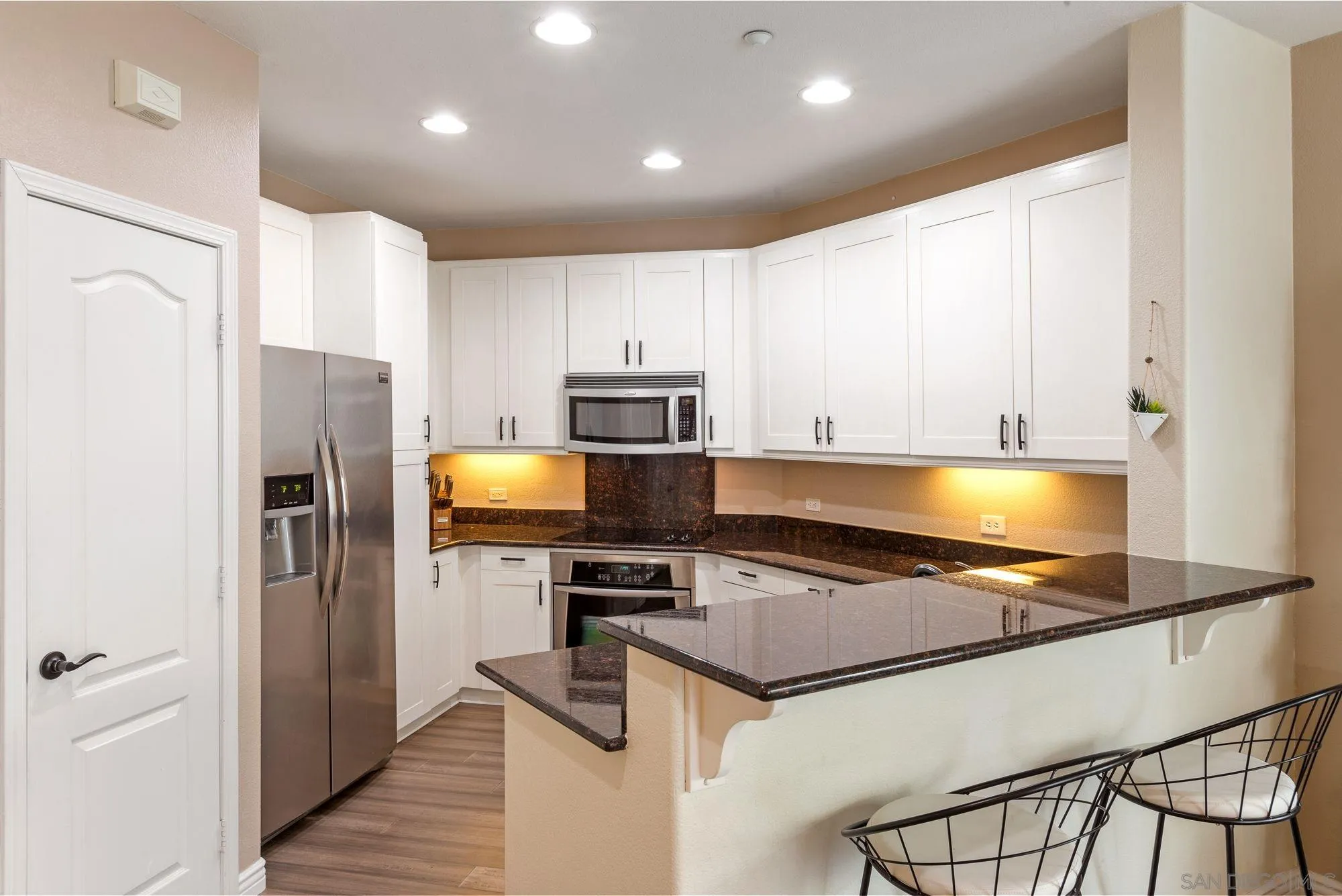 3957 30th Street, Unit 411 San Diego, CA 92104 - Photo 7 of 23 a kitchen with stainless steel appliances granite countertop a refrigerator a stove and a sink with wooden floor