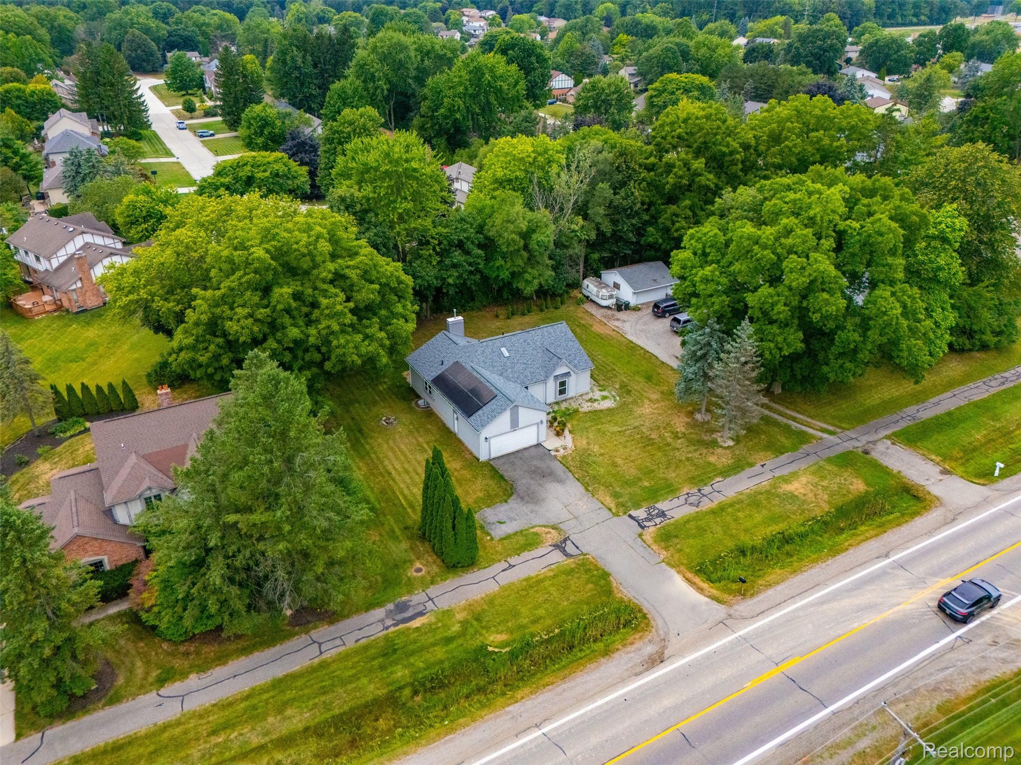 793 North Adams Road Rochester, MI 48309 - Photo 36 of 40 Single-family residence with a gray shingle roof and attached garage, situated on a verdant lot with mature trees