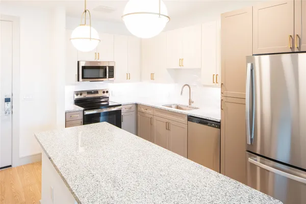 a kitchen with stainless steel appliances a refrigerator a stove a sink and a microwave
