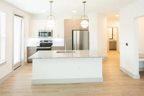 a view of kitchen island with stainless steel appliances granite countertop sink stove and refrigerator