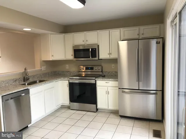 a kitchen with granite countertop a refrigerator sink and microwave